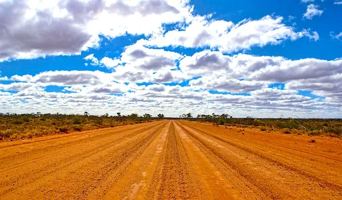 Jalan pedalaman Australia yang kosong dan berdebu pada hari yang cerah dan cerah