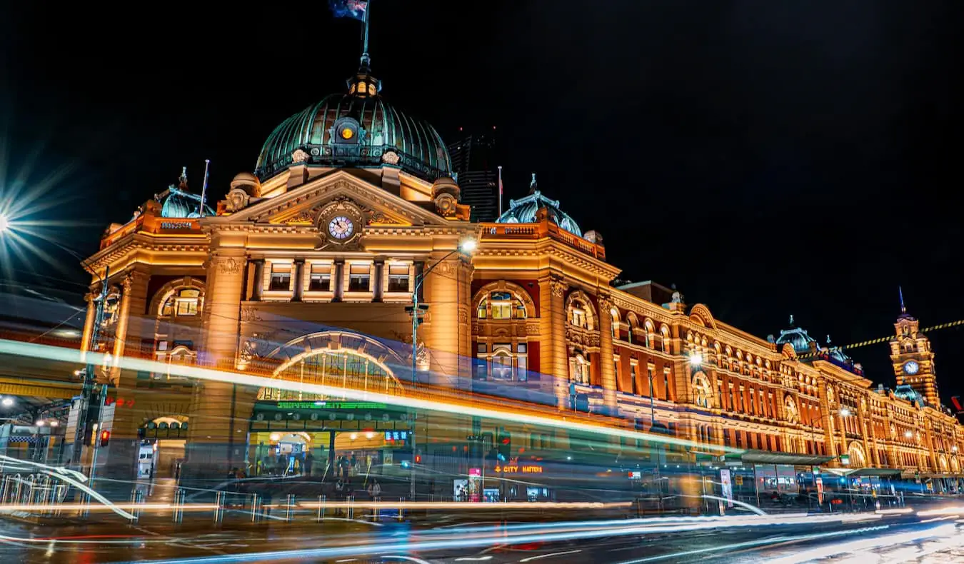 Историческата гара Flinders Street в Мелбърн, Австралия през нощта с преминаващ трафик