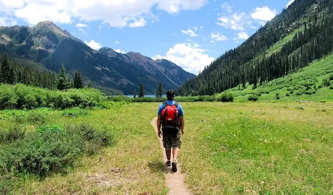 背包客在群山环绕的美丽草地上徒步旅行