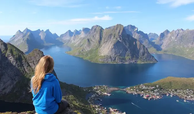 Vrouwelijke reiziger zit bovenop een berg en staart naar de overzeese oceaan