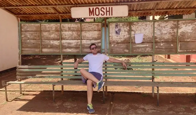 Mark Manson sidder ved et busstoppested i Moshi, Tanzania