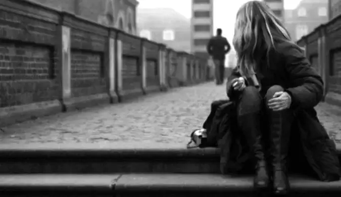 Una fotografía en blanco y negro de una mujer que viaja sola sentada en unas escaleras.