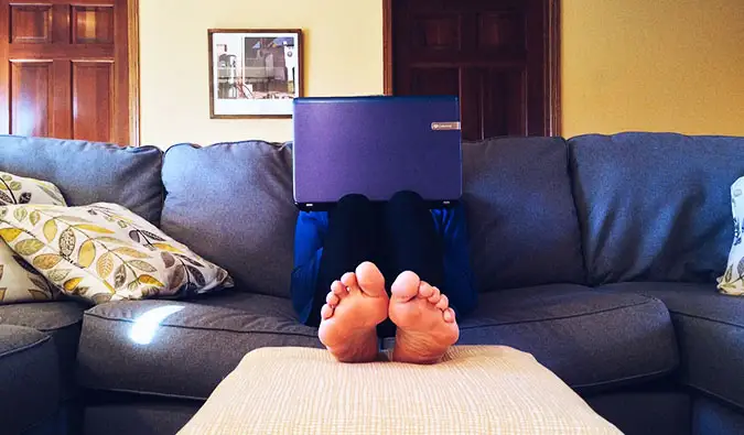 une personne assise sur le canapé avec un ordinateur portable