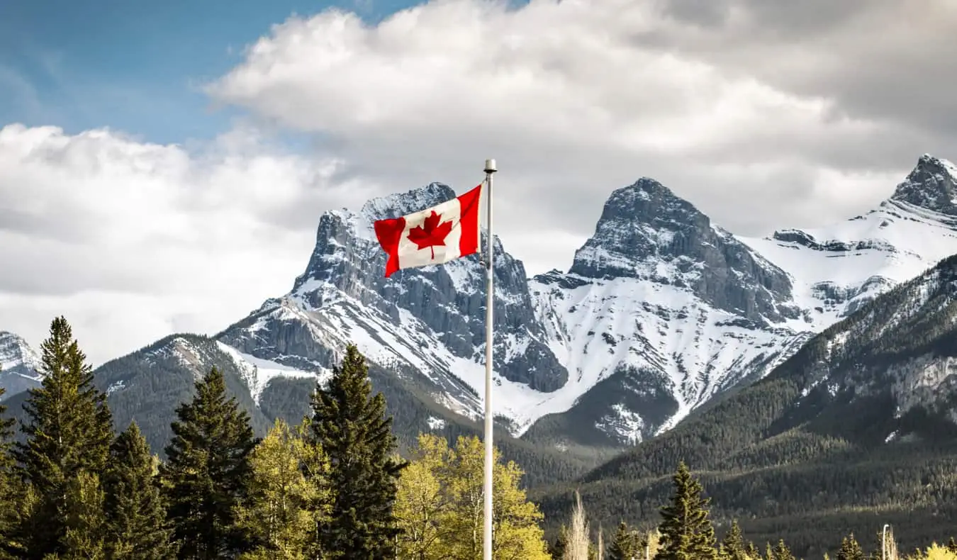 Uma bandeira canadense hasteada perto de uma montanha coberta de neve