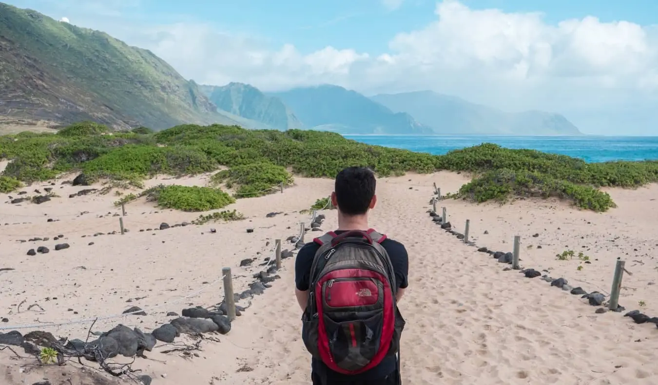 Nomadiske Matt iført ryggsekk mens han gikk langs en strand på Hawaii