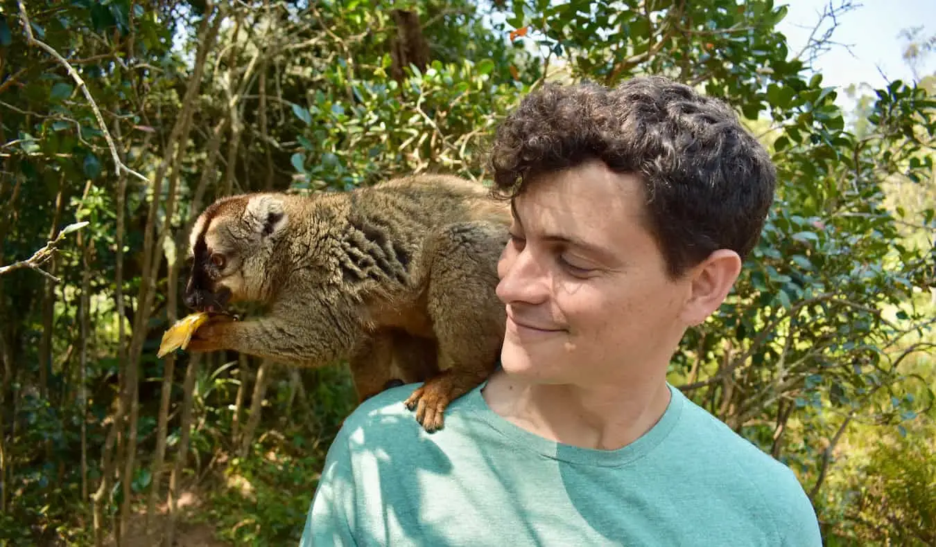 Il nomade Matt posa con un piccolo lemure nel lussureggiante Madagascar, Africa