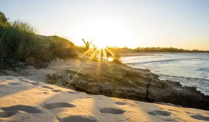 Amici sulla spiaggia in piedi nei raggi di luce