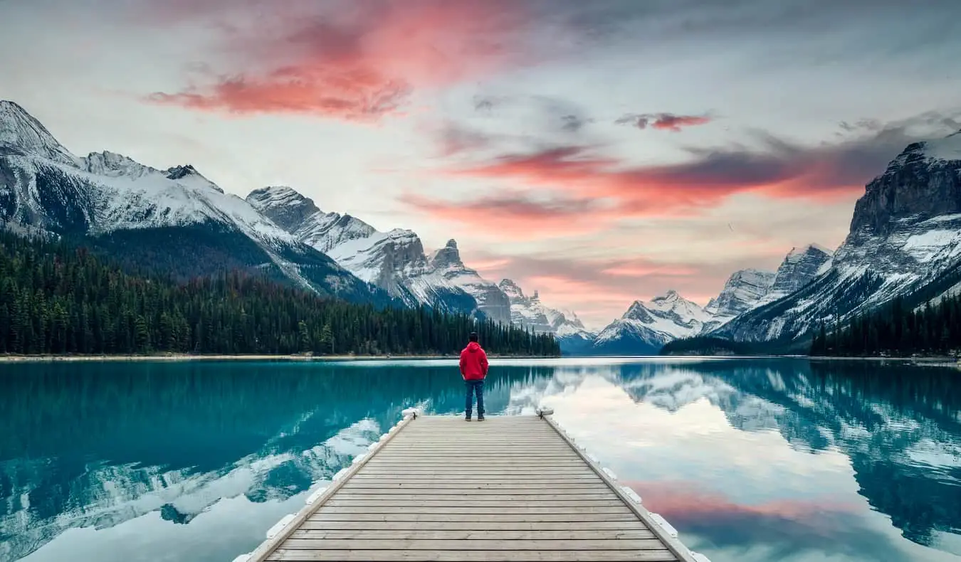 Một du khách đứng trên bến tàu được bao quanh bởi thiên nhiên ở vùng núi hiểm trở của Canada