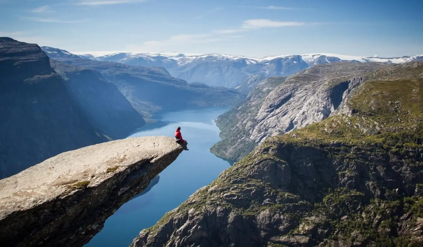 Osoba sjedi na stijeni Trolltunga iznad fjorda u Norveškoj