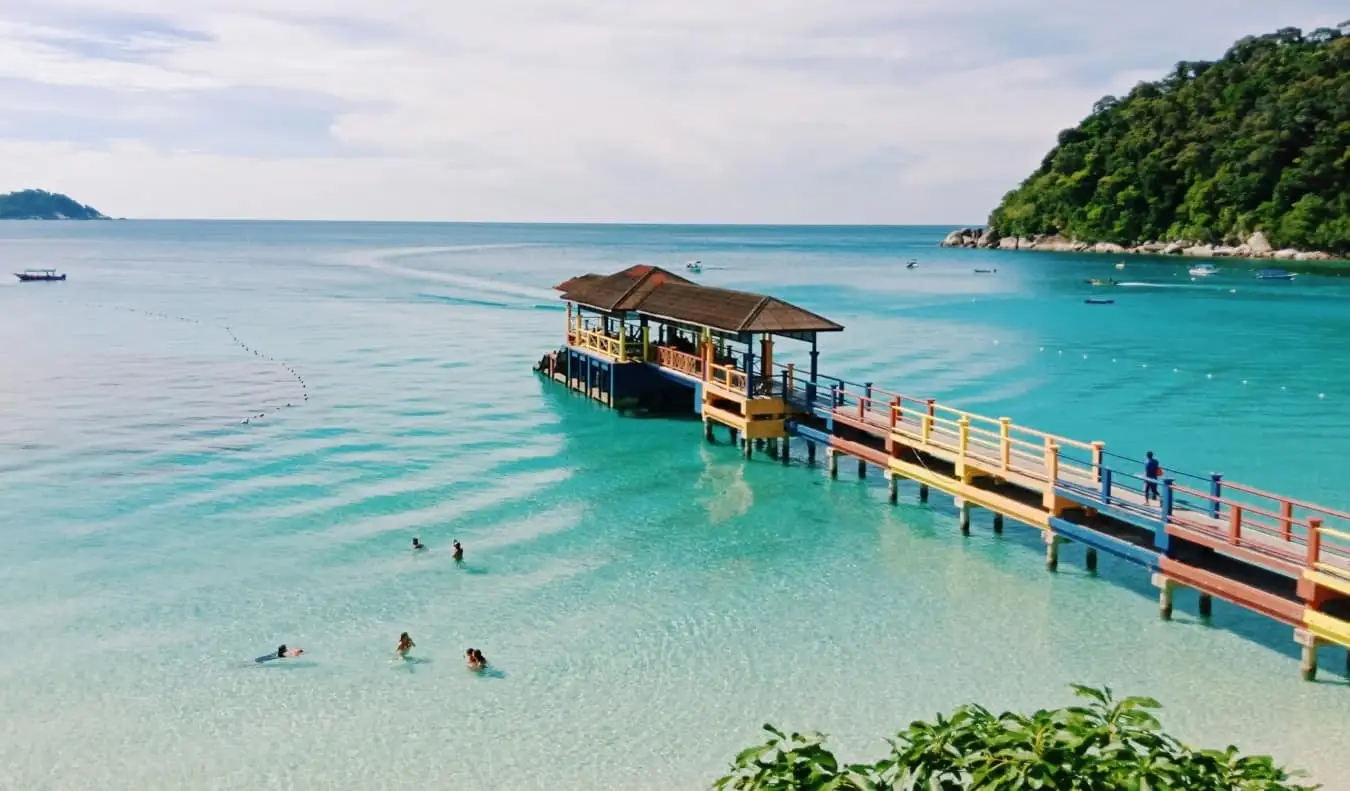 Colorido embarcadero que sobresale de las cristalinas aguas turquesas de una playa en las islas Perhentian, Malasia