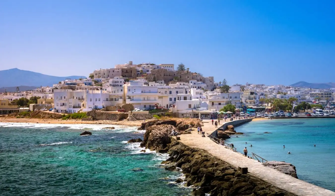 Gent caminant per una calçada de pedra que condueix al nucli antic emblanquinat de Naxos, Grècia