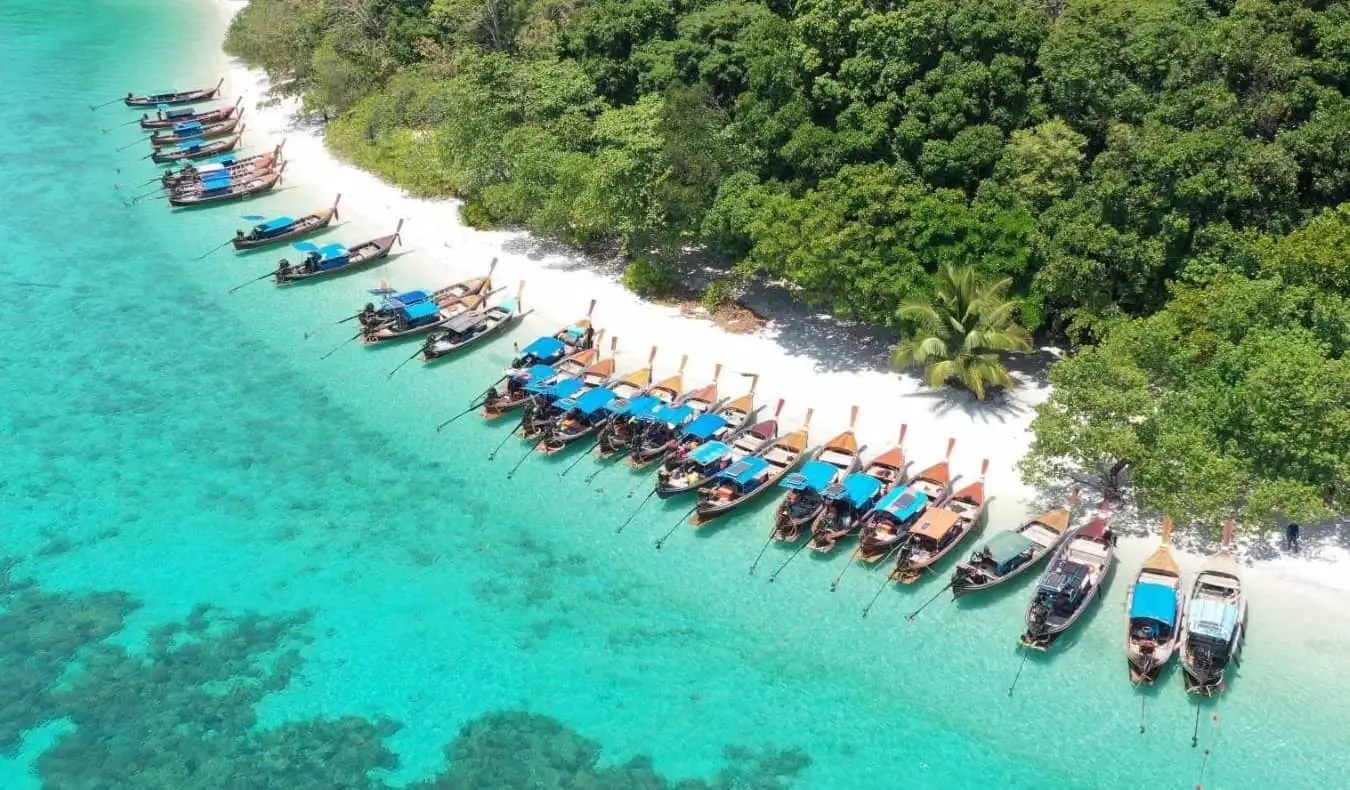 Vue aérienne d'une ligne de bateaux à longue queue amarrés sur une plage de l'île de Ko Lipe, en Thaïlande