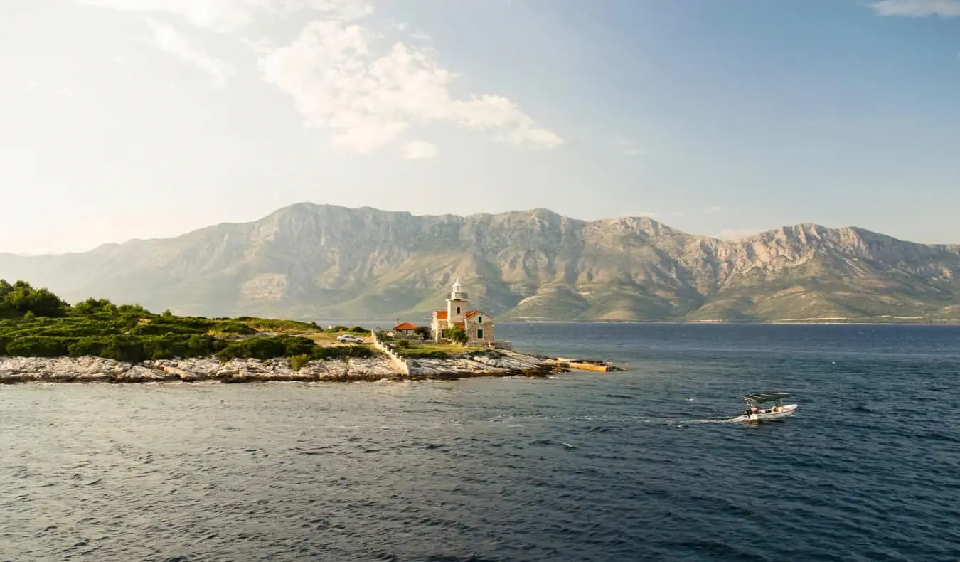 Izolovaná budova na pobřeží Hvar, Chorvatsko s horami v pozadí