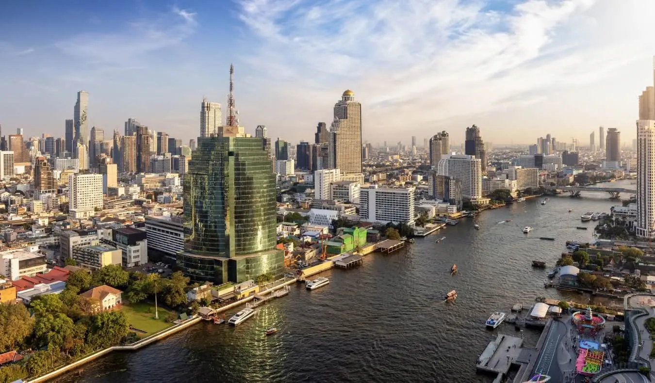 O horizonte de Bangkok, Tailândia, com arranha-céus erguendo-se em ambos os lados de um grande e sinuoso rio