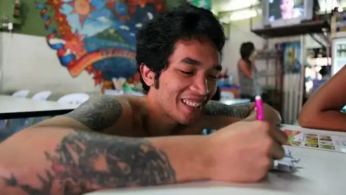 En lokal thailändsk man med tatueringar på en restaurang i Thailand