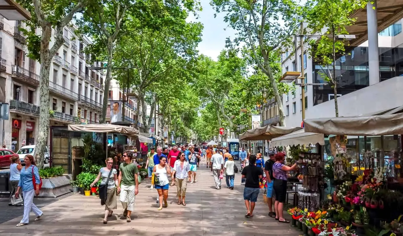 Lidé, kteří jdou po slavné pěší ulici La Rambla, se stánky lemujícími obě strany ve španělské Barceloně