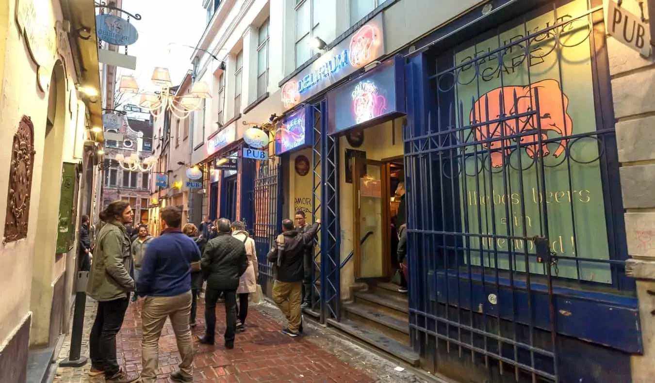 Menschen hängen in der Gasse neben dem Delirium Café, einer beliebten Brauerei in Brüssel, Belgien, herum und trinken etwas