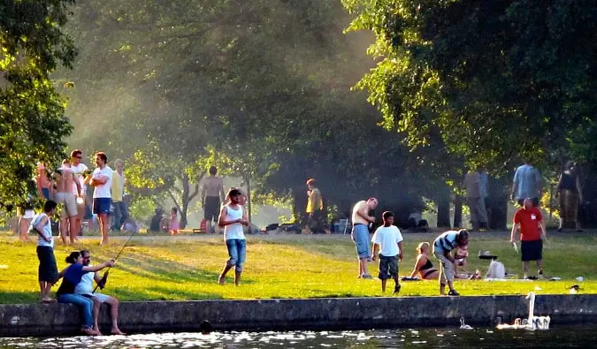 Emberek lógnak, beszélgetnek és horgásznak a Spree folyó partján a TrepTower Parkban Berlinben, Németországban