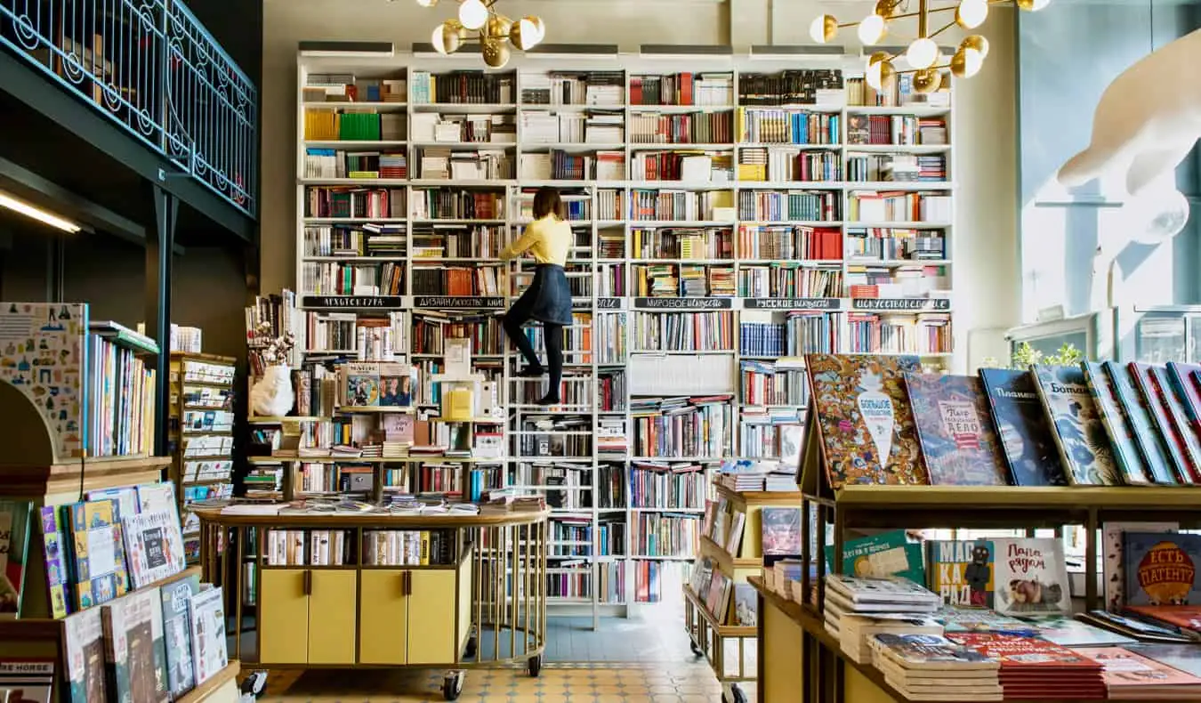 Una dona en una llibreria mirant llibres en una escala