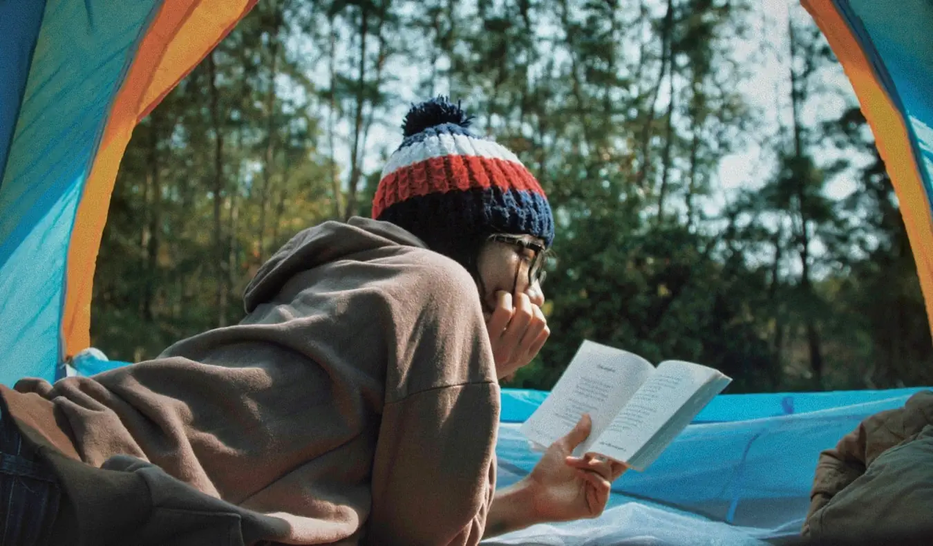 Un viatger llegint un llibre dins d'una tenda de campanya