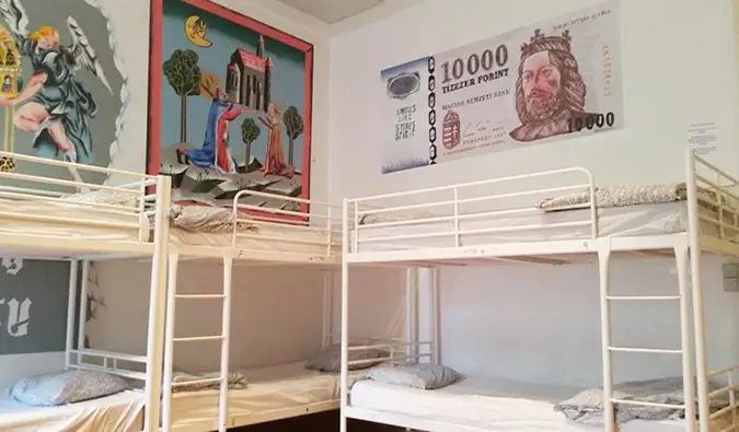 Våningssängar i sovsal med ungerska målningar på väggarna på Vitae Hostel, Budapest