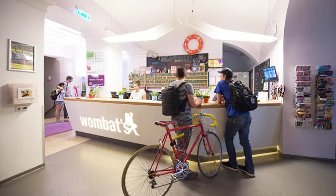 Twee mensen, één met een fiets, checken in bij de receptie van het Wombats Hostel, Boedapest