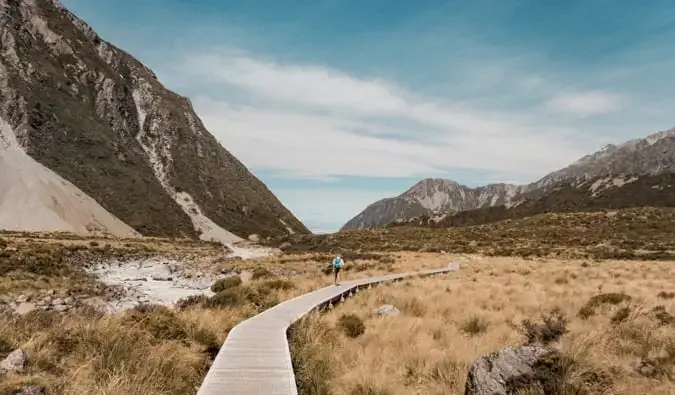 Ein Alleinwanderer, der auf einem Holzsteg im malerischen Neuseeland unterwegs ist