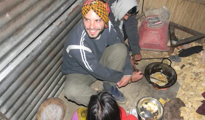 Un voyageur solo cuisinant avec une famille d'accueil dans une petite cabane à l'étranger