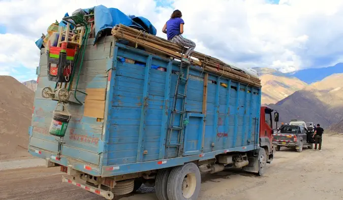 Seorang backpacker membonceng di atas sebuah trak di Peru