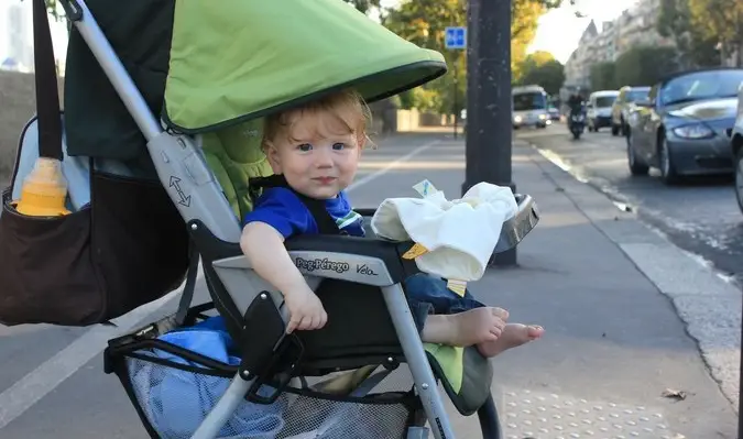 Un bambino carino che sorride alla macchina fotografica nel passeggino mentre viaggia all'estero