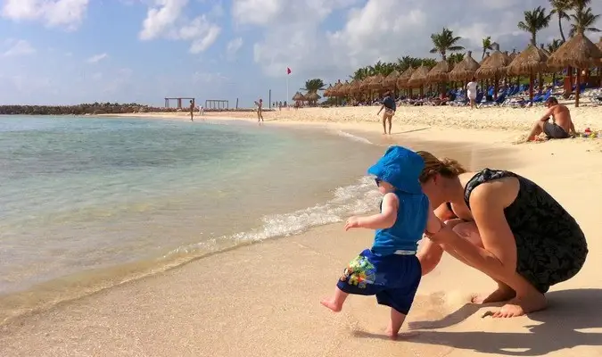 Seorang bapa bermain dengan anak kecilnya di dalam air di pantai