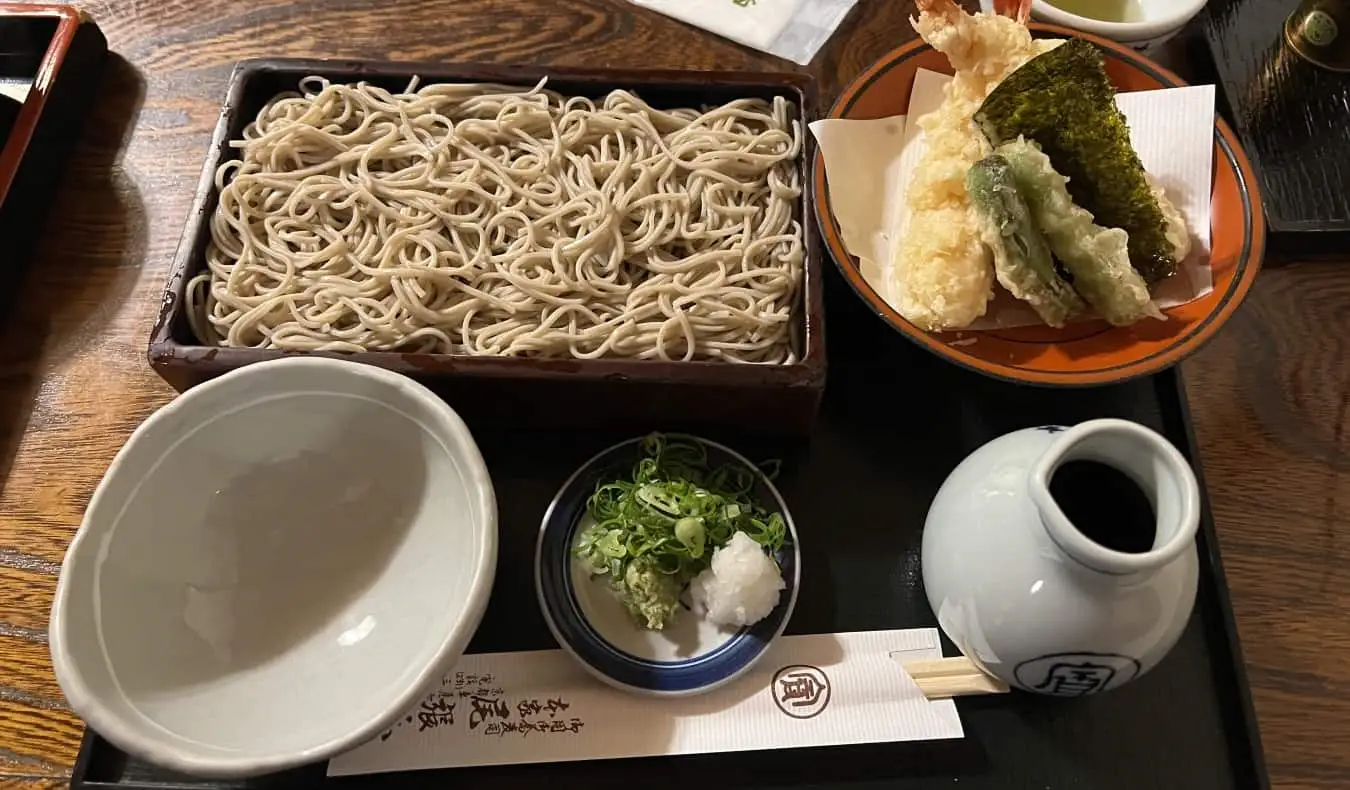 Un ensemble de ramen avec des nouilles, du tempura, un pot de sauce soja et un bol vide dans un magasin de ramen au Japon