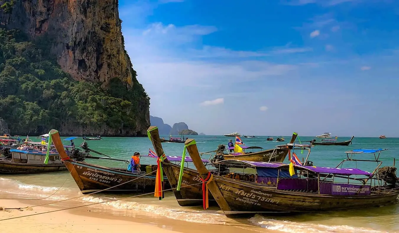 Barcos de cola larga estacionados en una hermosa playa en una isla de Tailandia