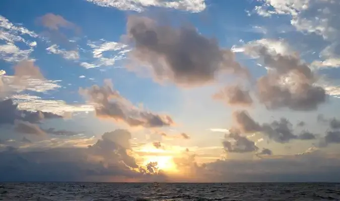 oblačen sončni zahod nad vodo na Maldivih