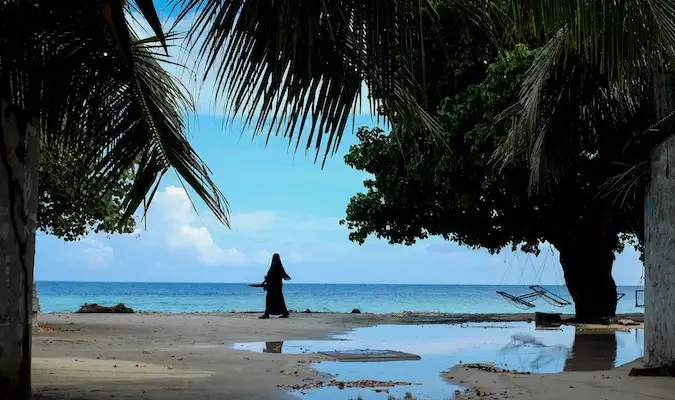 O femeie musulmană locală care se plimbă de-a lungul plajei din Maldive