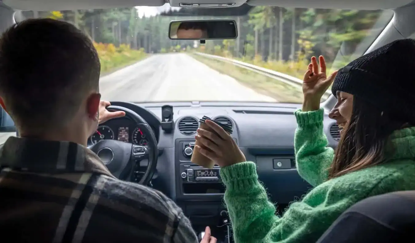 Un hombre y una mujer en el asiento delantero de un coche.