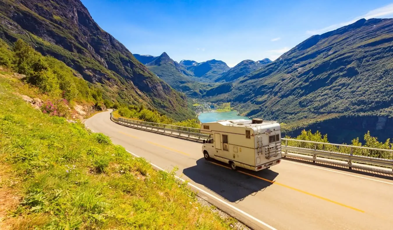 Una casa rodante recorre una carretera sinuosa a través de un pintoresco paisaje montañoso