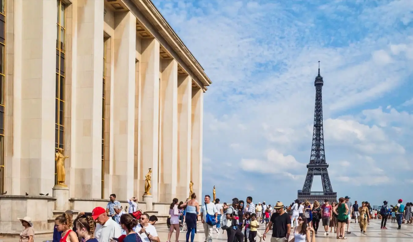 Une foule de voyageurs près de la Tour Eiffel sous le soleil de Paris