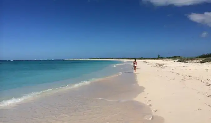 En reisende som går nedover en strand i de vakre BVI-ene