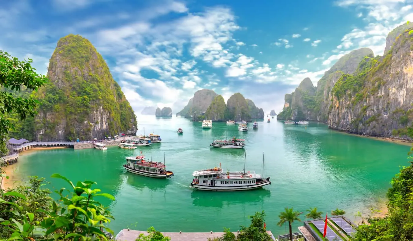 Barche nelle calme acque della baia di Ha Long vicino ad Hanoi, Vietnam, circondate da alte montagne