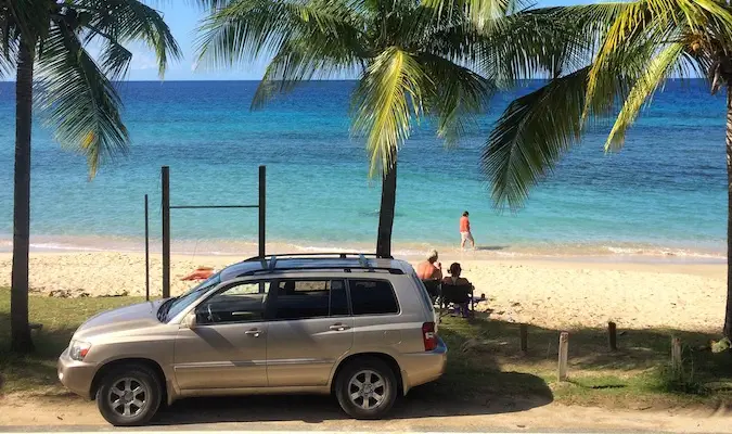 Sebuah mobil diparkir di dekat pantai indah di Cane Bay di USVI