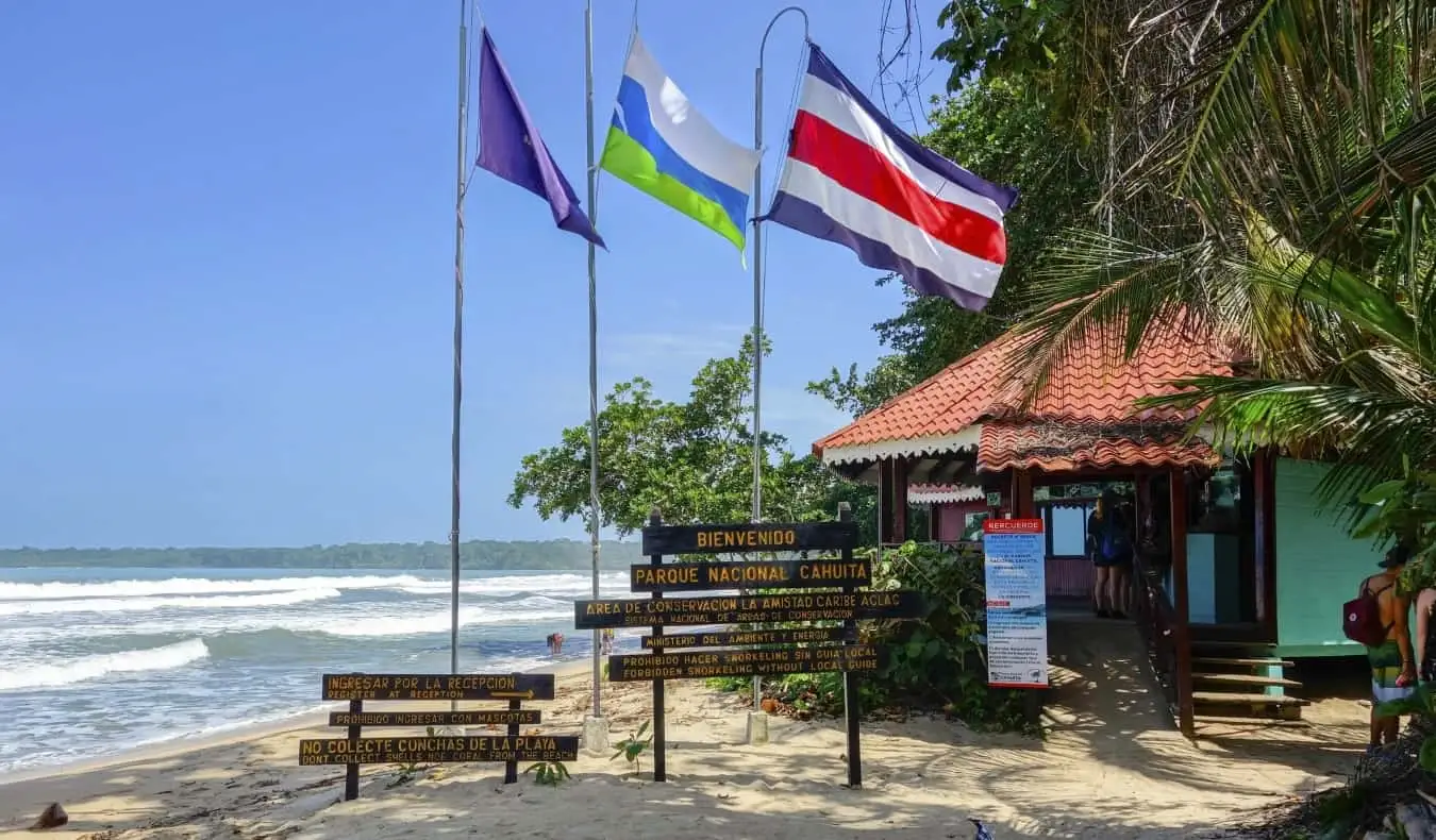 A Costa Rica-i Cahuita Nemzeti Park bejárata táblákkal és zászlókkal