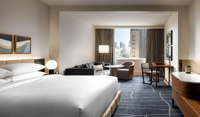 O cameră mare, cu un pat king-size, canapea, zonă de relaxare, ferestre mari, toate decorate într-un design contemporan minimal la hotelul Park Hyatt din Toronto, Canada