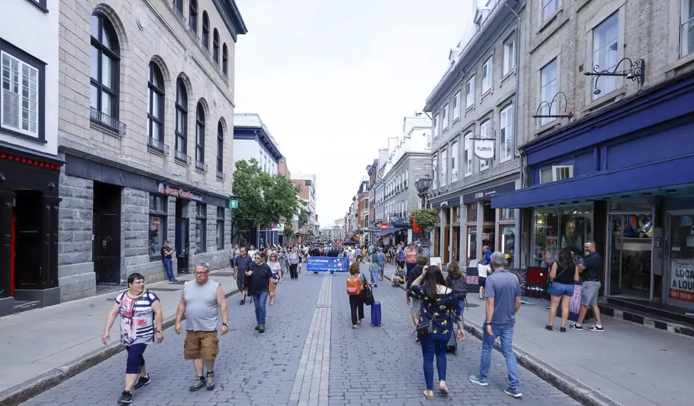 Ihmiset kävelevät keskellä mukulakivistä rue Saint-Jeania kesällä, kun se