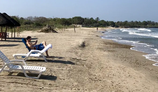 Písečná pláž s několika turisty, kteří odpočívají za slunečného dne v Cartageně