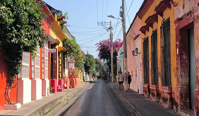 Helder geschilderde gebouwen langs een smalle, lege straat in Cartagena, Colombia