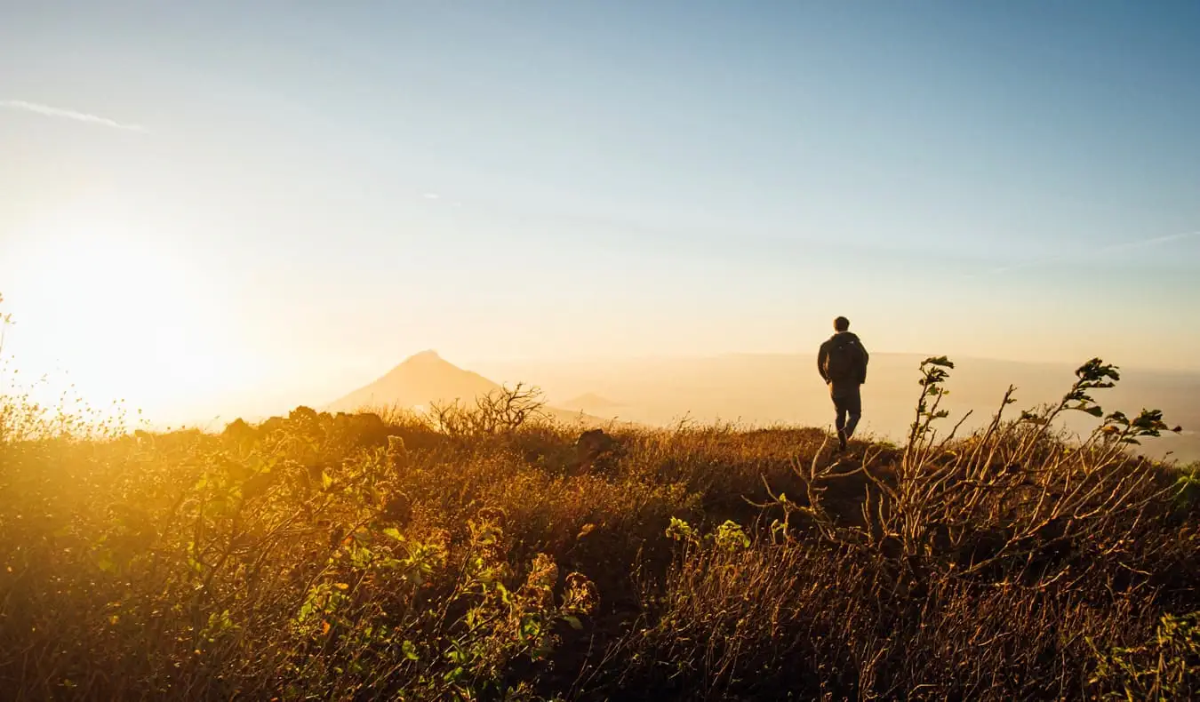 Um homem caminhando nas montanhas perto de Leon, Nicarágua, durante um pôr do sol brilhante