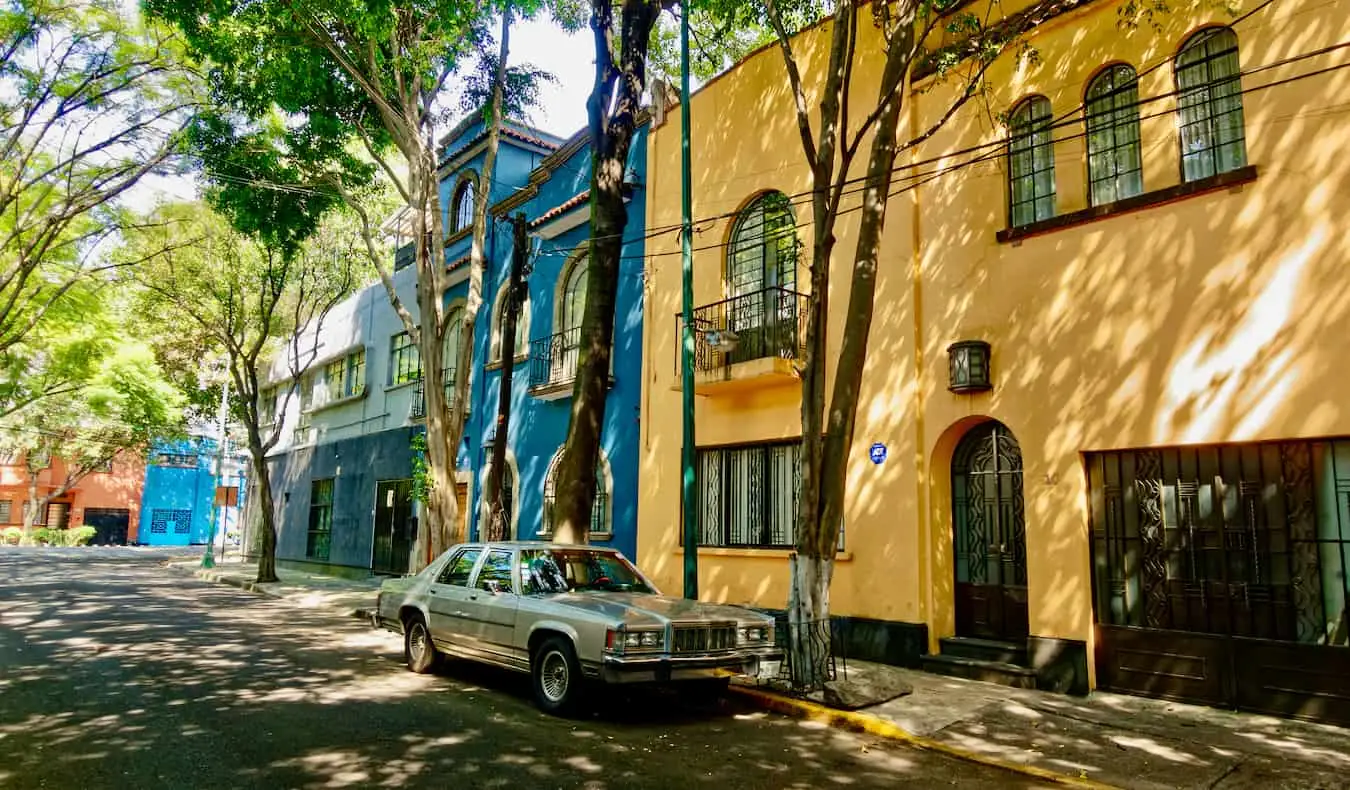 En lugn gata med färgglada hus i Condesa, Mexico City med en bil parkerad på gatan