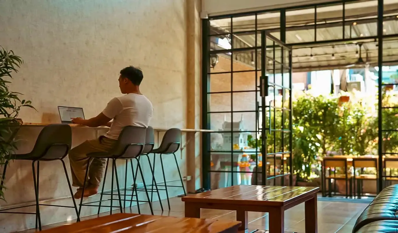 Um viajante solitário trabalhando em uma mesa no Stamps Hostel em Chiang Mai, Tailândia