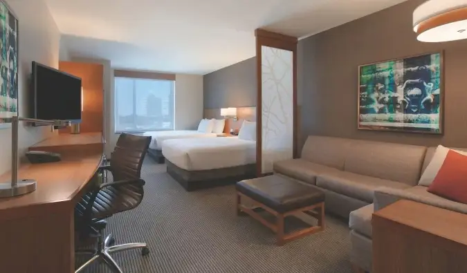 Gästezimmer im Hyatt Place Chicago South mit zwei Queensize-Betten, einem Schreibtisch und einer großen Sofagarnitur